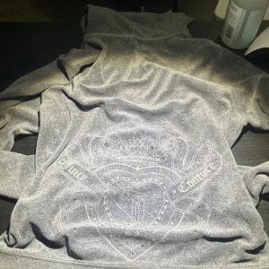 Grå hoodie från Juicy Couture - Den är xl fast passar S!!  en snygg grå hoodie från Juicy Couture med dragkedja och huva. Tröjan har ett elegant emblem på ryggen och är perfekt för en avslappnad stil. Den är mjuk och bekväm, idealisk för kyliga dagar.