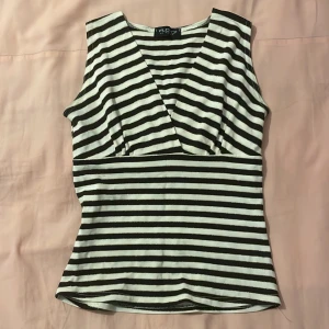 Randig ärmlös topp från Floyd by Smith - Snygg ärmlös topp från Floyd by Smith med svartvita ränder och en v-ringad design. Perfekt för en stilren look.