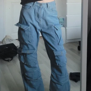 Blå jeans - Säljer ett par blå cargojeans med flera fickor (inga fejk fickor). De har en loose fit och hade sagt att de är mid waist. Har använts få antal gånger och är i fint skick. Det är från Fashion Chingu, kostar ungefär 500 kr nypris. 