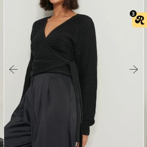 Svart omlottstickad tröja - Svart omlottstickad tröja från NAKD med långa ärmar och knytband i midjan. Använd ett få tal gånger men som ny. Säljer den pga att den inte kommer till användning💗