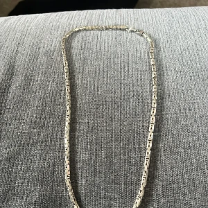 Silverfärgat halsband - Elegant silverfärgat halsband med ett unikt kedjemönster. Perfekt för att ge en stilren touch till din outfit.