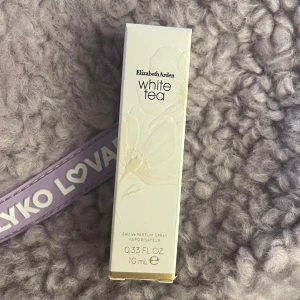 Elizabeth Arden White Tea Eau de Parfum - Elegant och fräsch parfym från Elizabeth Arden, White Tea, i en stilren glasflaska med vit kork. Innehåller 10 ml och är perfekt för att bära med sig. Doften är lätt och uppfriskande, inspirerad av vita teblad.