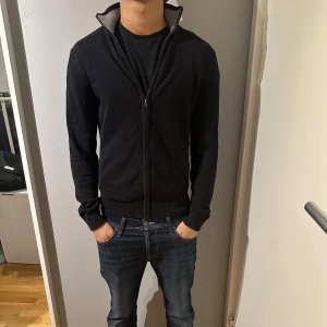 Full zip  - Tja, säljer nu en Snygg svart kofta med dragkedja och hög krage. Tröjan är i toppen skick utan defekter. 
