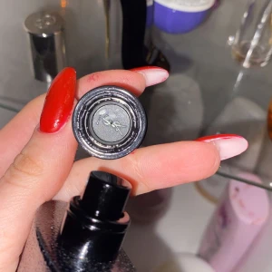 Svart parfymflaska från Yves Saint Laurent - Elegant svart parfymflaska från Yves Saint Laurent med en stilren design. Flaskan har en rund form och ett metalliskt lock med märkets logotyp. Perfekt för den som söker en lyxig doftupplevelse.