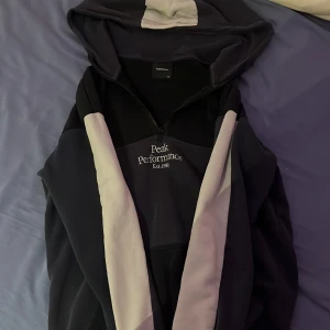 Peak performance kofta - Hoodie, mysig och skön. Passar både män och kvinnor. Den är mörkblå i helhet med svarta och vita detaljer med en ficka i mitten. 