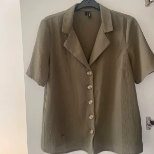 Olivgrön topp  - Säljer en stilren olivgrön topp med korta ärmar. Passar både till vardags och fest! Köpt på vero Moda och använd ett fåtal gånger, storlek S. 💗✨ (Fläcken på bilden var endast en vattenfläck) 