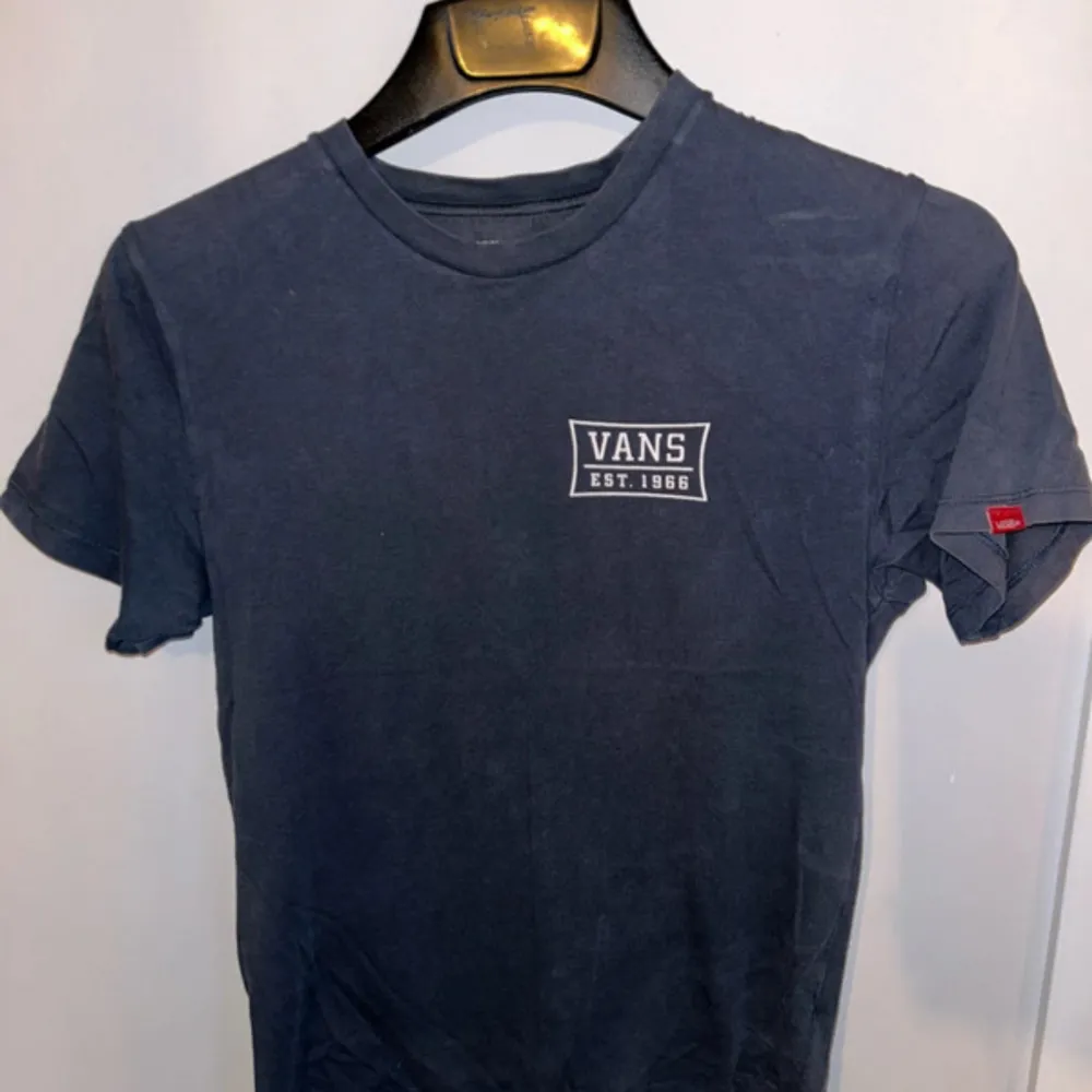 Säljer en snygg mörkblå t-shirt från Vans med tryck 'Vans Est. 1966' både fram och bak. Den är gjord i 100% bomull och är superbekväm. Perfekt för vardagsbruk eller en avslappnad dag ute. T-shirten är i storlek small och har korta ärmar.. T-paidat.