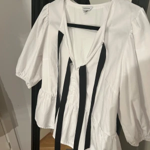 Vit topp med knyte  - En super fin topp från bubbleroom med ballongärmar. Den svarta banden kan man knyta till små söta rosetter. Den är i ett fint skick och bara använd 1 gång och har inga defekter. Den är i storlek M