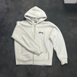 Stussy Zip Up Hoodie - Säljer denna sjukt feta stussy zipup hoodien i strl L. Extremt fint skick och sparsamt använd. Köpt i deras affär i London där jag har digitalt kvitto. Denna kommer aldrig gå att köpta ny igen, din chans att slå till! Skriv gärna vid intresse och för fler bilder!