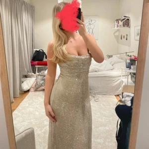 Glittrig axelbandslös klänning - Säljer en elegant axelbandslös klänning i glittrande champagnefärg. Klänningen är lång och figurnära, perfekt för en festlig kväll och bal. Använd en gång😇Är 171cm💕