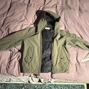 Grön jacka från Stone Island - Säljer en grön jacka från Stone Island med huva och dragkedja. Jackan har två fickor med knappar och är tillverkad med Primaloft isoleringsteknik. Perfekt för kyligare dagar och för regn skick 7/10 eftersom den har 3 små hål som man kan se om man kollar noga på bilderna skicka gärna frågor om jackan om ni är intresserade priset är ej hugget i sten mvh Benjamin 