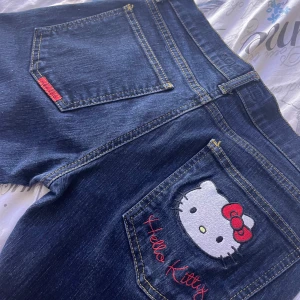Hello Kitty jeans - Mörkblå jeans med ett sött Hello Kitty-broderi på bakfickan.  Jag skulle säga att det är straight jeans och dom är väldigt lågmidjade.Skulle säga att den passar storlek 32 eller 34 då den är lite liten för mig som brukar ha storlek 36. Jag tror den inte säljs längre och det är även äkta Sanrio. Det finns inga defekter.priset går att diskuteras!