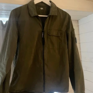 Grön jacka från C.P. Company - Snygg grön overshirt från C.P. Company. Overshirten är i storlek S. knappar finns på armen vid handleden. perfekt till sommaren och våren!