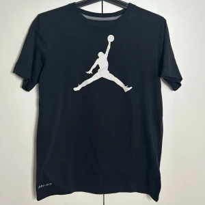 Svart Jordan Dri-FIT t-shirt  - Säljer en svart Dri-FIT t-shirt från Jordan med den klassiska vita loggan på framsidan. Perfekt för sport och vardag. Köpt i USA och hittar inget kvitto. Om ni har fler frågor så skriv! (Priset är inte spikat)
