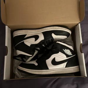 Nike Air Jordans i svart och vit - Säljer ett par klassiska Nike Air Jordans i svart och vit. Skorna har en ikonisk design med snörning och den välkända loggan på sidan. Perfekta för dig som vill ha en stilren och sportig look.