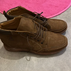 Bruna boots med snörning - Snygga bruna boots från The Boos med snörning och robust sula. Tillverkade i skinn med detaljerad sömnad. Perfekta för en stilren look.