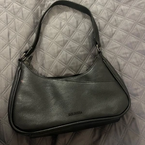 Svart axelväska från Don Donna - Snygg svart axelväska från Don Donna. Väskan har knappt några tecken på användning 
