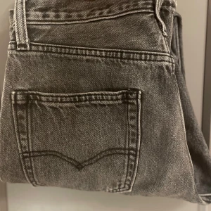 Grå jeans från Levi's - Snygga grå jeans från Levi's med klassisk femficksdesign. De har en rak passform och är tillverkade i slitstarkt denim. Perfekta för en avslappnad stil.