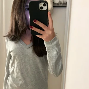Grå tröja från Tommy Hilfiger - Säljer en jättesnygg grå tröja från Tommy Hilfiger med v-ringning. Tröjan har långa ärmar och en liten logga. Kontakta mig för frågor eller köp.💕
