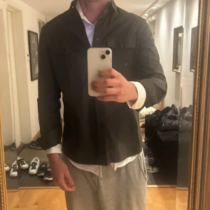 Olivgrön overshirt från Calvin Klein - Säljer en stilren olivgrön overshirt från Calvin Klein. Skjortan har en fitted passform och är långärmad med knappar framtill. Perfekt för en avslappnad men ändå uppklädd look.