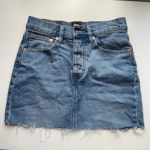 Jeanskjol från Lager 157 - Snygg jeanskjol från lager 157 i klassisk blå denim. Kjolen har en kort längd med fransig botten. Perfekt för sommaren.