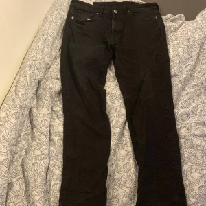 Svarta jeansbyxor från H&M - Snygga svarta jeansbyxor från H&M i straight modell med regular fit. Perfekta för en stilren look. Tillverkade i Bangladesh.