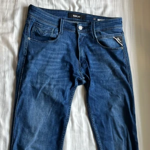 Blå jeans från Replay - Snygga blå jeans från Replay med klassisk femficksdesign och knappgylf. Perfekta för en avslappnad stil. Midjan är w29 och längden är 32. Märkeslappen i läder baktill ger en extra touch.