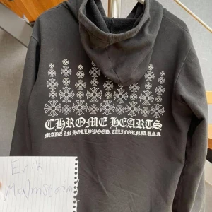 Svart hoodie från Chrome Hearts - Säljer en svart hoodie från Chrome Hearts med dragkedja och tryck i vitt på både fram- och baksidan. Hoodien har en klassisk passform med långa ärmar och en justerbar huva. Perfekt för en stilren och avslappnad look. Tar emot bud