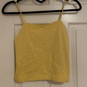 Gul linnetopp från XOXO Friends - Säljer en söt gul linnetopp från XOXO Friends. Toppen har smala axelband och en enkel design som passar perfekt för varma dagar. Perfekt för att lägga till en färgklick i garderoben! Storlek 158-164