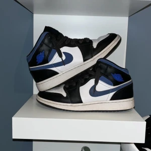 Jorden 1 Racer Blue - Snygga Jorden 1 Racer Blue, vit och blå med klassisk snörning. Perfekta för dig som vill ha en stilren och sportig look. Skorna har en ikonisk design med det välkända Nike-märket på sidan.