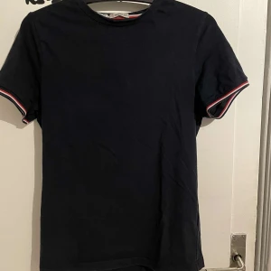 Marinblå t-shirt från Moncler - Snygg marinblå t-shirt från Moncler med korta ärmar och diskret logga på ärmen. Perfekt för en stilren look. Hör av er vid minsta fundering🤔Nypris 2100kr