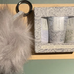 *NY*Secret Garden Handkrämskollektion, presenttips  - Säljer ett presentset från Secret Garden innehållande tre handkrämer (Lemon Grass & Cotton Flower & Lavender Dreams) i resevänliga tuber, 3x30ml. Medföljer gör även en fluffig grå nyckelring.  (Nya oanvända förpackningen har fått ett litet skav på hörnet, satt en bit tejp över.)