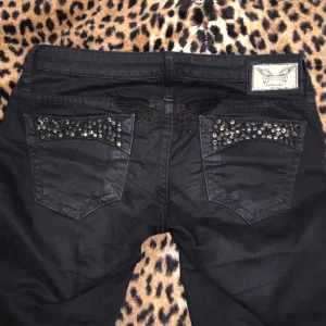 Svarta Lågmidjade Robin's Jeans  - Snygga svarta jeans från Robin's Jean med coola nitar på bakfickorna. Jeansen har en lågmidjad passform och är perfekta för en edgy stil. Märkeslogga synlig på insidan av linningen. De är skinny men går lätt att göra om till bootcut!❤️Skicka prisförslag!!