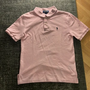 Ralph Lauren piké - Säljer en stilren rosa pikétröja från Ralph Lauren. Tröjan har en klassisk krage med knappar. Den är perfekt för en avslappnad men ändå elegant stil. Kan gå ner i pris.