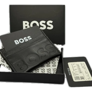 BOSS Black Original Leather Card Holder With 05 x Card Slots. -   New Hugo Boss GENUINE LEATHER card holder for men - This stylish card holder is made of high-quality leather and has enough space for cards and cash. Ideal for the modern man who appreciates stylish accessories. A must-have for every occasion and an elegant addition to the wardrobe.   ⁃        02 slots on each side and 01 in the middle on top. ⁃        New with Tags And Original Box & tissue  