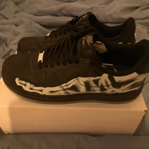 Svarta Nike Air Force med skelettmönster - Snygga svarta Nike Air Force med unikt skelettmönster i vitt på sidorna och botten lyser i mörker om dom har fått ljus på dom använda några gånger bara 