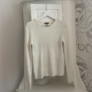 Vit ribbad tröja från Massimo Dutti - Säljer en stilren vit ribbad tröja från Massimo Dutti. Tröjan har långa ärmar och en klassisk rund halsringning. Perfekt för en elegant och avslappnad look.