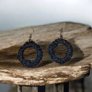 Svarta örhängen knutna med makramé - Unika handgjorda örhängen i svart material. De har en rund form och hänger från en enkel krok i metall. Perfekta för att ge en bohemisk touch till din stil.