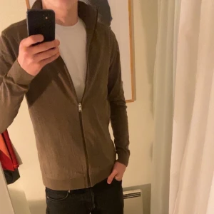 Brun kofta med dragkedja - Säljer en stilren brun kofta med dragkedja framtill. Perfekt för lager-på-lager och har långa ärmar. Passar bra till både vardag och mer avslappnade tillfällen.