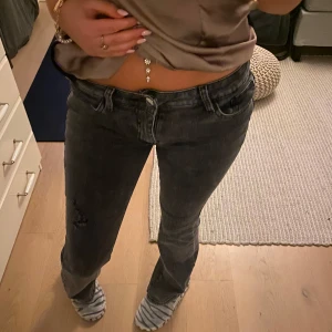 Gråa jeans med slitningar - Snygga grå jeans med en tight passform och slitningar på ena benet. 