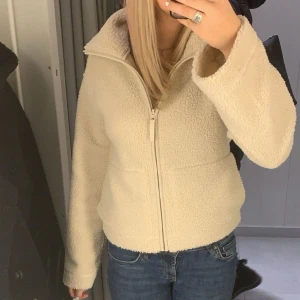 Beige teddyjacka med dragkedja - Populär beige teddyjacka från H&M som är slutsåld. Perfekt för kyliga dagar med sin fluffiga och varma design. Jackan har en hög krage och långa ärmar. 🥰 Lägg gärna prisförslag