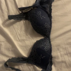 mörkblå intimissimi spets-bh - Elegant svart bh med vacker spetsdetaljering. Den har en klassisk design med justerbara axelband och en bekväm passform. Den är i storlek 75B från intimissimi och är i modellen push up!