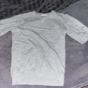 Grå sweatshirt - Säljer en stilren grå sweatshirt med rund hals och trekvartsärmar. Perfekt för en avslappnad look. Passar bra till jeans eller joggers.väl använd utan defekter