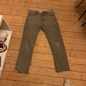 Grå jeans från Jack & Jones - Säljer ett par grå jeans från Jack & Jones. De har en klassisk straight passform och är tillverkade i slitstarkt denim. Perfekta för en avslappnad stil.