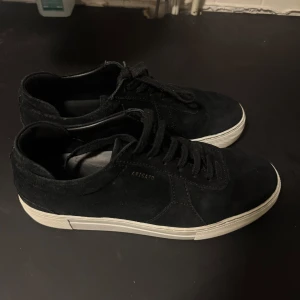 Svarta sneakers från Axel Arigato - Snygga svarta sneakers från Axel Arigato i mocka med vit sula. Skorna har klassisk snörning och en stilren design som passar perfekt till vardags. Perfekta för dig som gillar en minimalistisk stil. Sparsamt använda.