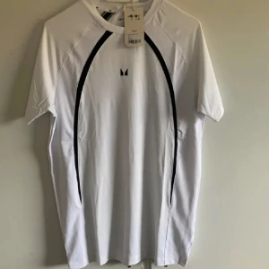 Vit t-shirt från MP - Snygg vit T-shirt från MP med svarta detaljer längs sidorna. Perfekt för träning eller en avslappnad dag. Tillverkad av återvunnet material. Nypris 399kr 