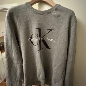 Grå tröja från Calvin Klein  - Tja, Säljer denna tröja från Calvin Klein. Tröjan är i bra skick och används inte då den är för liten för mig! 