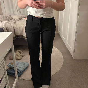 Svarta kostymbyxor - Snygga svarta kostymbyxor med en bootcut-stil. De har en låg midja och det är medellen med slits nertill. Fint skick och passar till allt. Bara att skriva för fler bilder. 