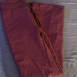 Vinröda mjukisbyxor - Säljer ett par bekväma vinröda mjukisbyxor med dragsko i midjan. Perfekta för en avslappnad dag hemma eller en snabb tur till affären. Byxorna har en enkel design utan mönster.