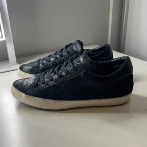 Philippe model skor - Ett par svart glittriga Philippe model skor i bra skick. Har små defekter på undersulan och är lite smutsiga på sulan. Storlek 40 och passar bra för både män och kvinnor! Inget og medföljer 